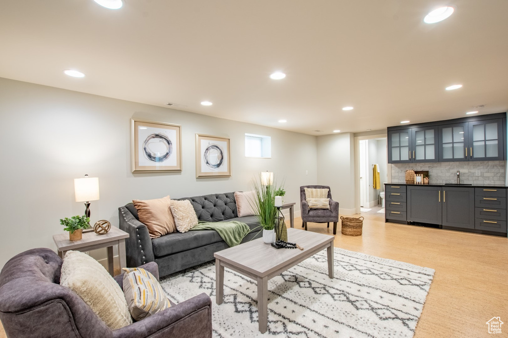 Living room with bar with sink, light wood-type flooring, and recessed lighting