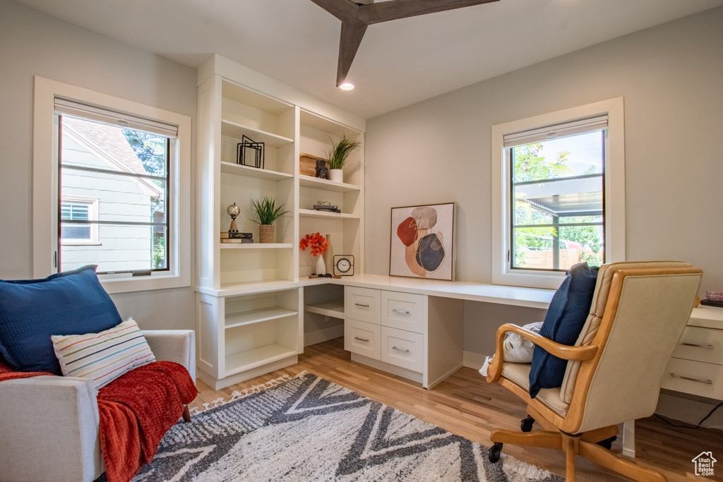 Office area with light wood-style flooring, healthy amount of natural light, built in desk, and recessed lighting