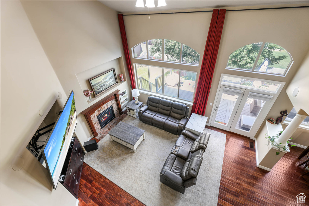 Living area with a towering ceiling, a glass covered fireplace, and wood finished floors