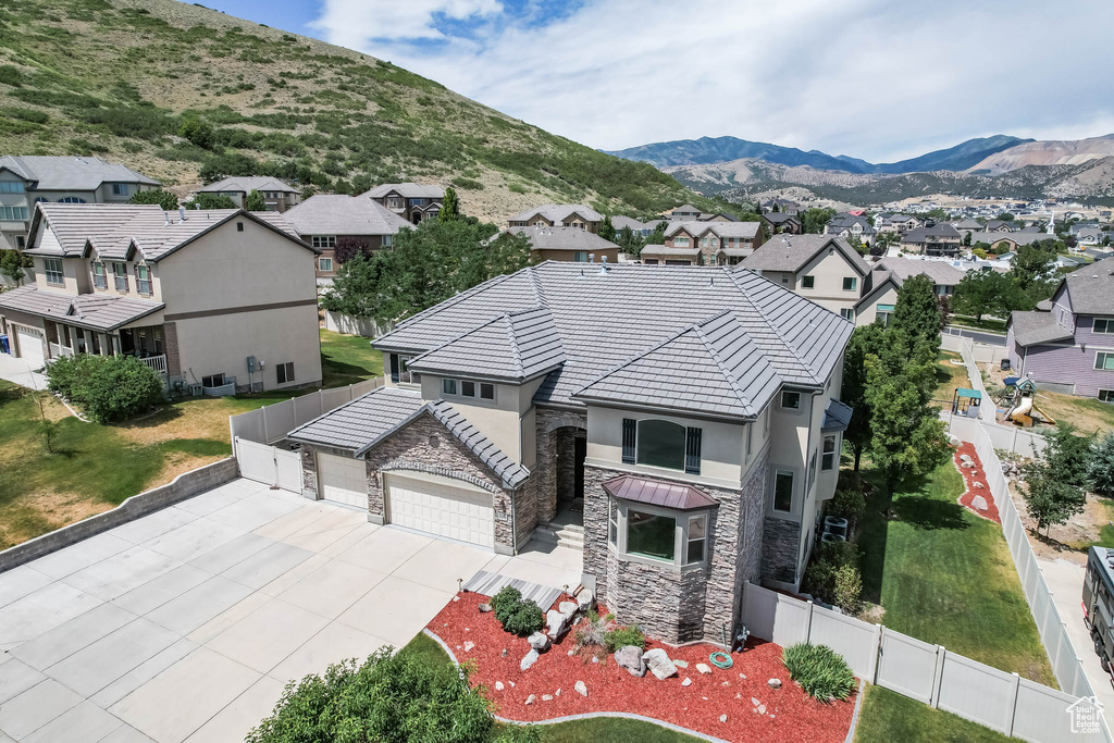 View of front of home with stone siding, a residential view, driveway, and a garage