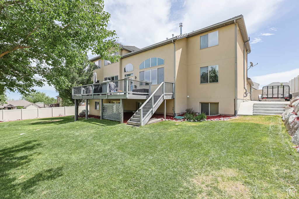 Rear view of property featuring stairs, stucco siding, and a deck