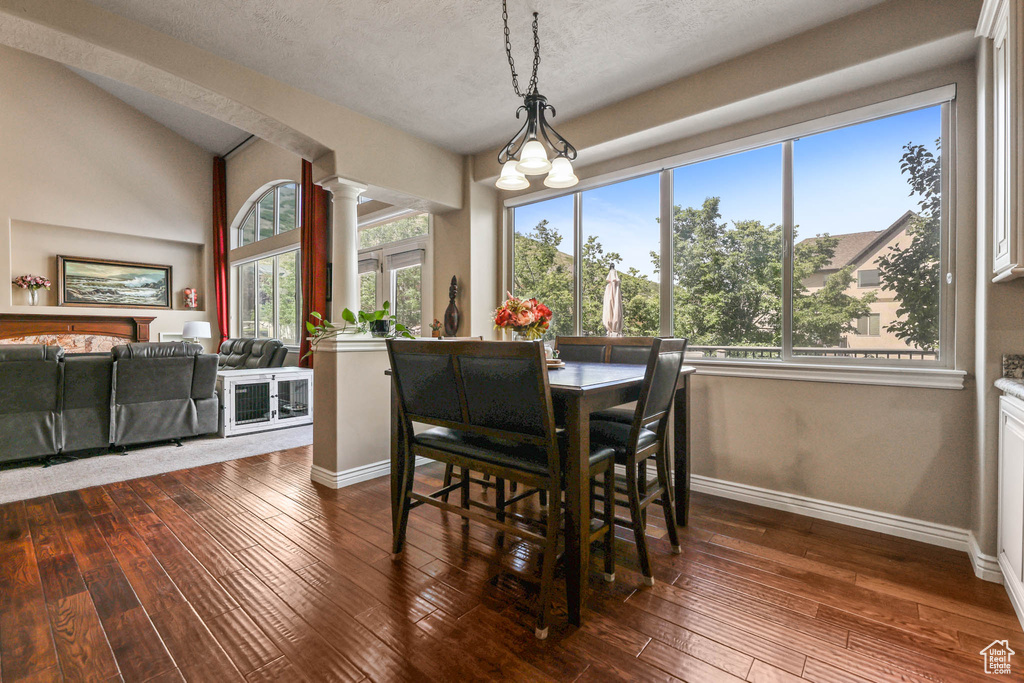 Dining area with decorative columns, dark wood-style flooring, and a textured ceiling