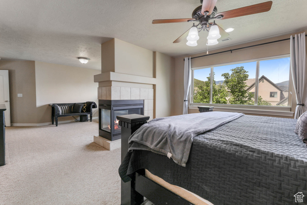 Bedroom with carpet, a textured ceiling, a fireplace, and a ceiling fan
