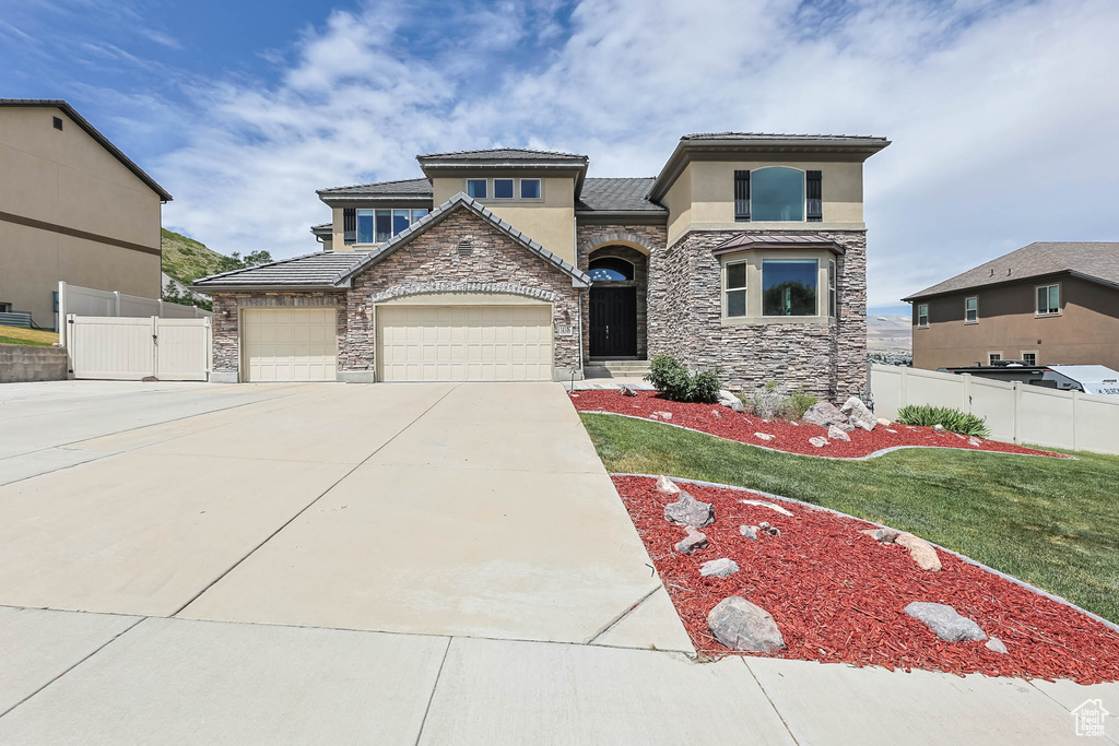 View of front of home with stone siding, stucco siding, concrete driveway, and an attached garage