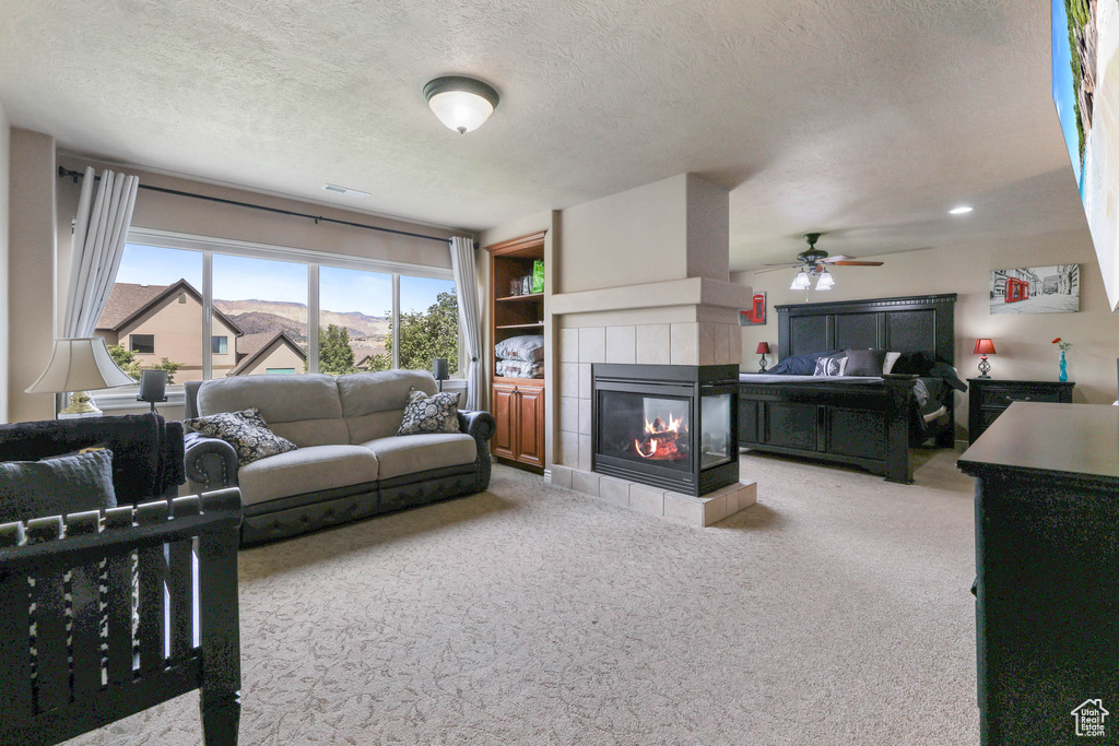 Living room with carpet floors, a fireplace, a textured ceiling, and ceiling fan