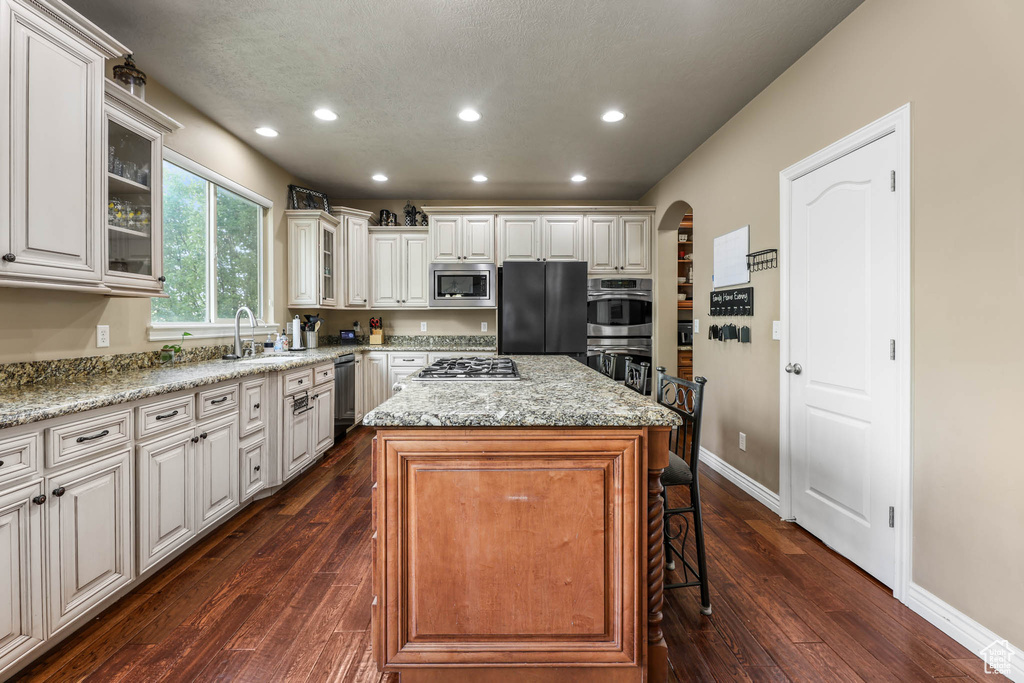 Kitchen featuring appliances with stainless steel finishes, arched walkways, recessed lighting, a breakfast bar, and a center island
