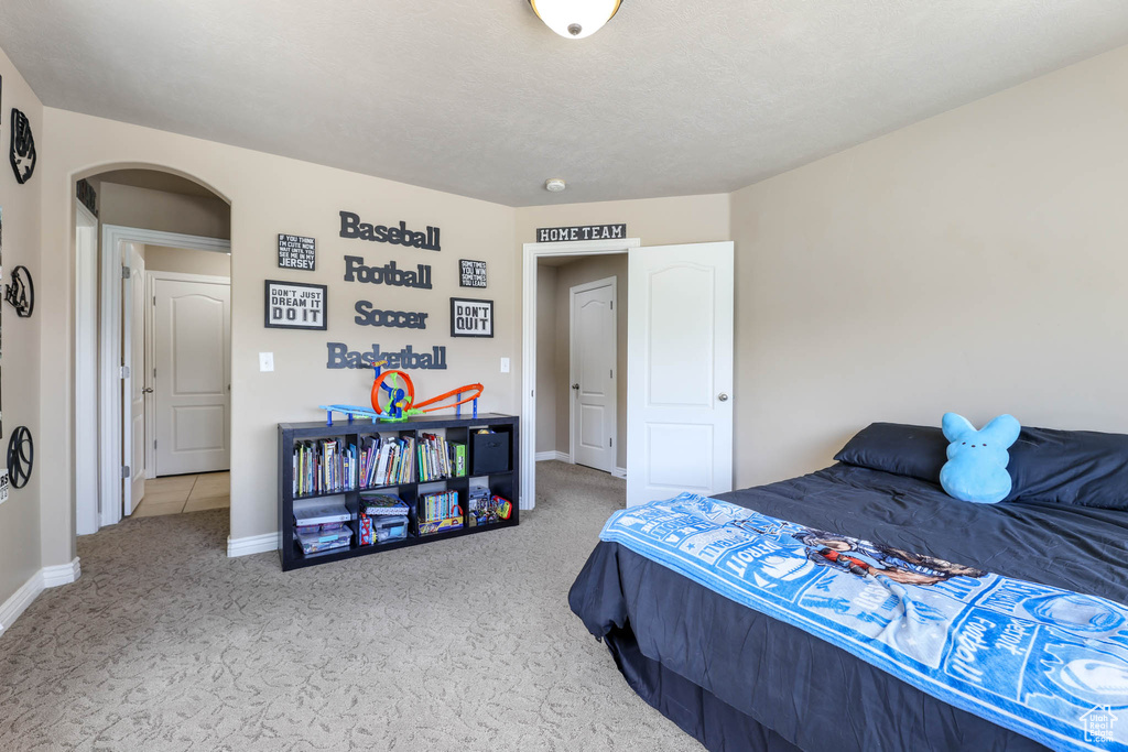 Bedroom featuring arched walkways and carpet flooring