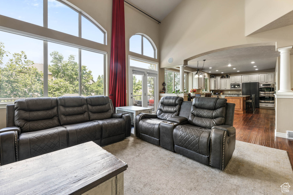 Living room with decorative columns, dark wood-style floors, and a high ceiling
