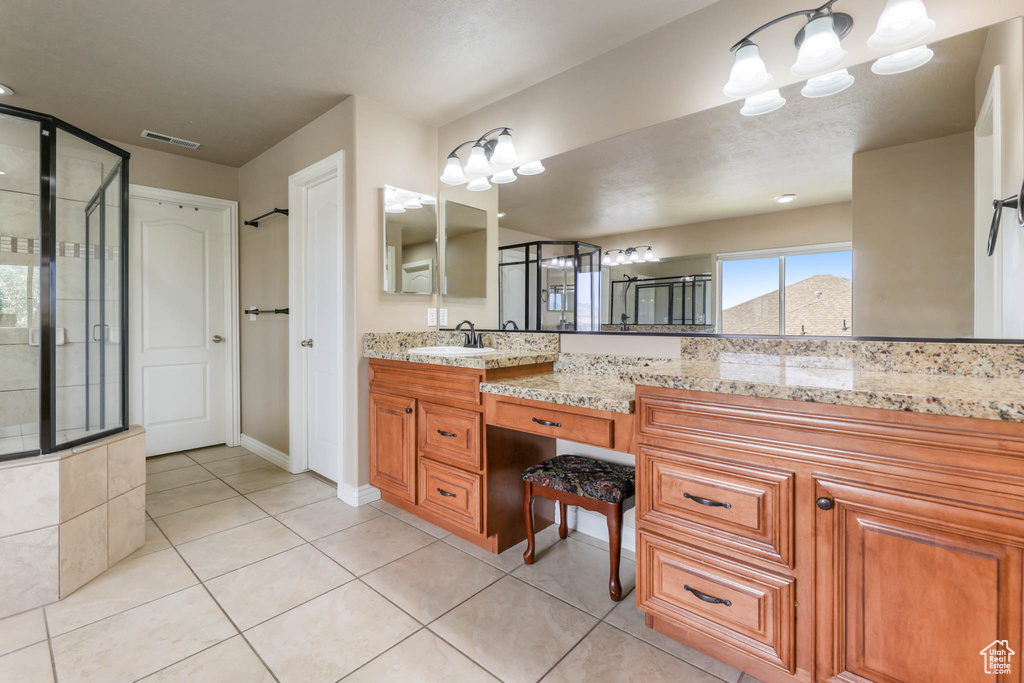 Full bathroom featuring double vanity, tile patterned flooring, and an enclosed shower