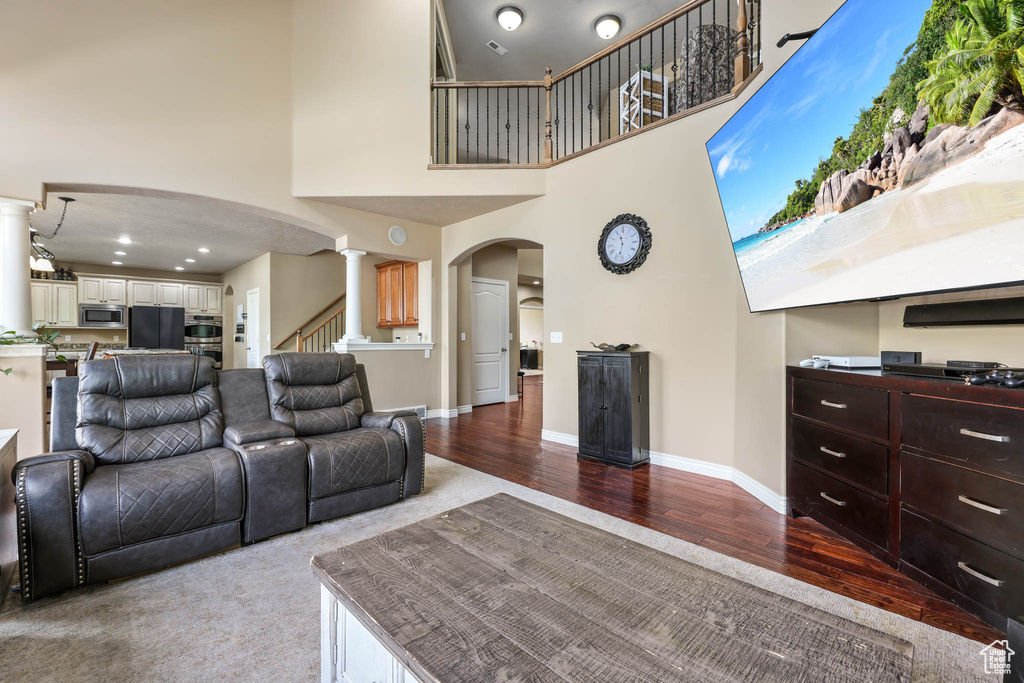 Living area featuring arched walkways, a high ceiling, wood finished floors, and stairs