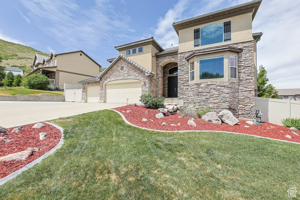 View of front of house with stone siding, stucco siding, a garage, and driveway