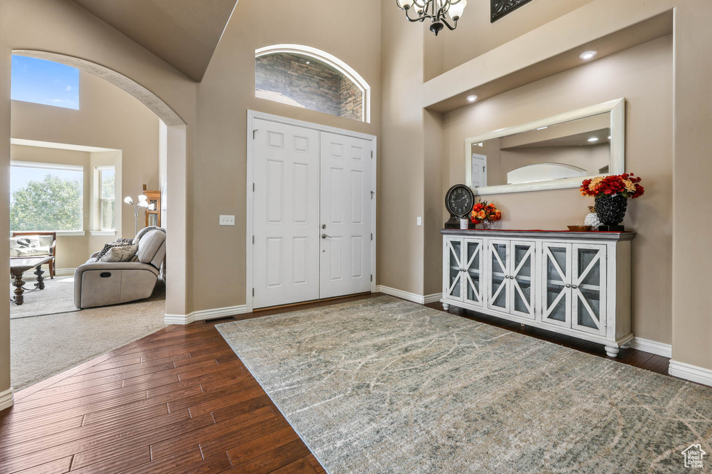 Foyer entrance with arched walkways, wood-type flooring, and high vaulted ceiling