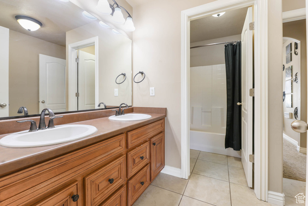 Full bath featuring double vanity, tile patterned floors, and shower / bath combo