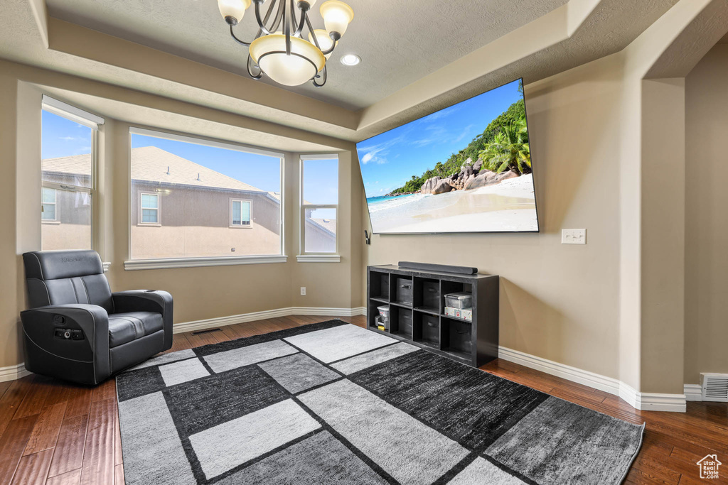 Living area featuring hardwood / wood-style floors, a tray ceiling, a chandelier, and plenty of natural light