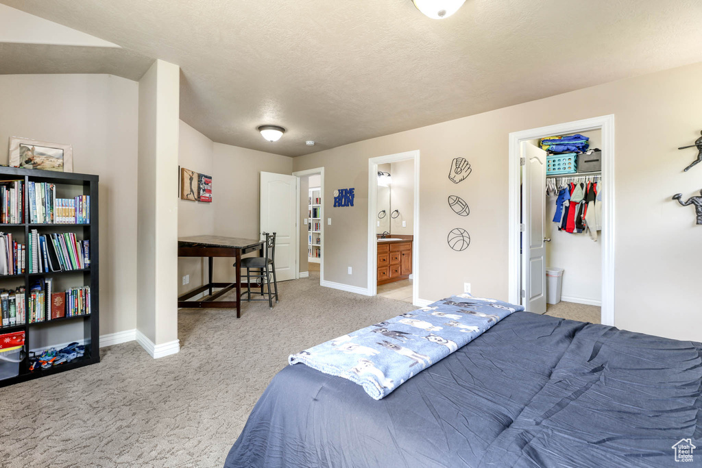 Bedroom with carpet floors, ensuite bath, and a walk in closet