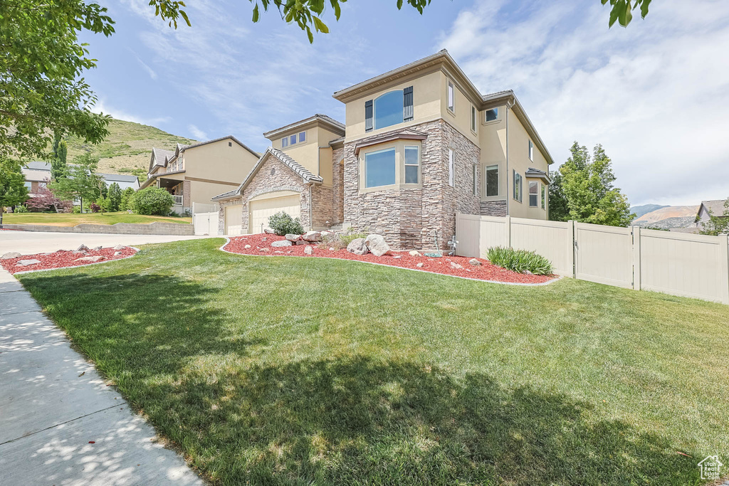 View of front of home with stone siding, stucco siding, and an attached garage