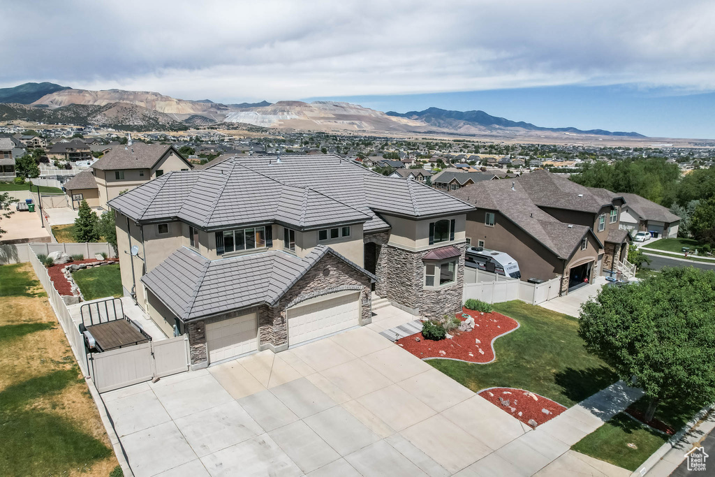 View of front facade featuring stone siding, stucco siding, a gate, concrete driveway, and a residential view