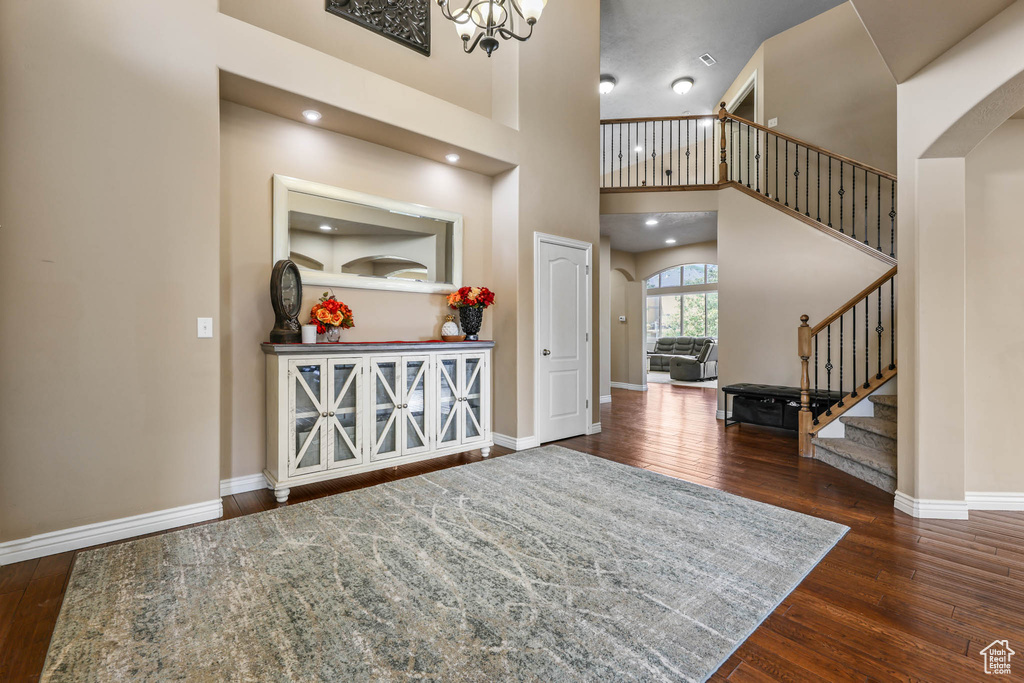 Foyer entrance with arched walkways, stairway, wood finished floors, and a towering ceiling