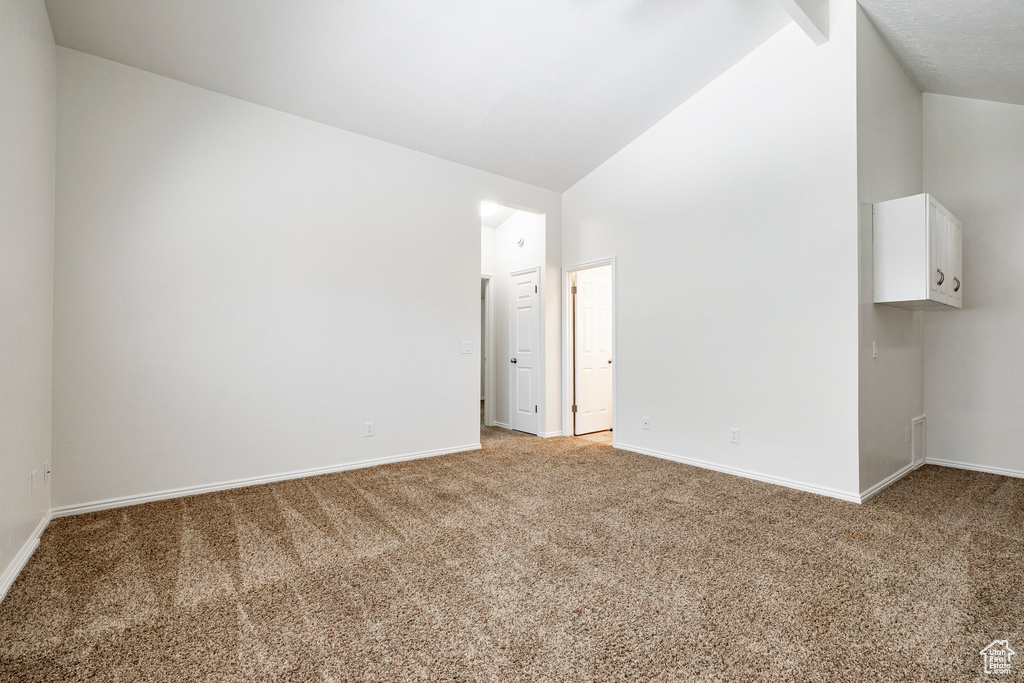 Unfurnished room with light carpet and lofted ceiling