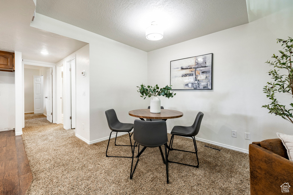 Carpeted dining space featuring wood finished floors and a textured ceiling