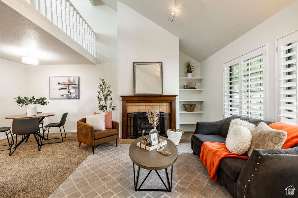 Carpeted living area with a high ceiling and a fireplace