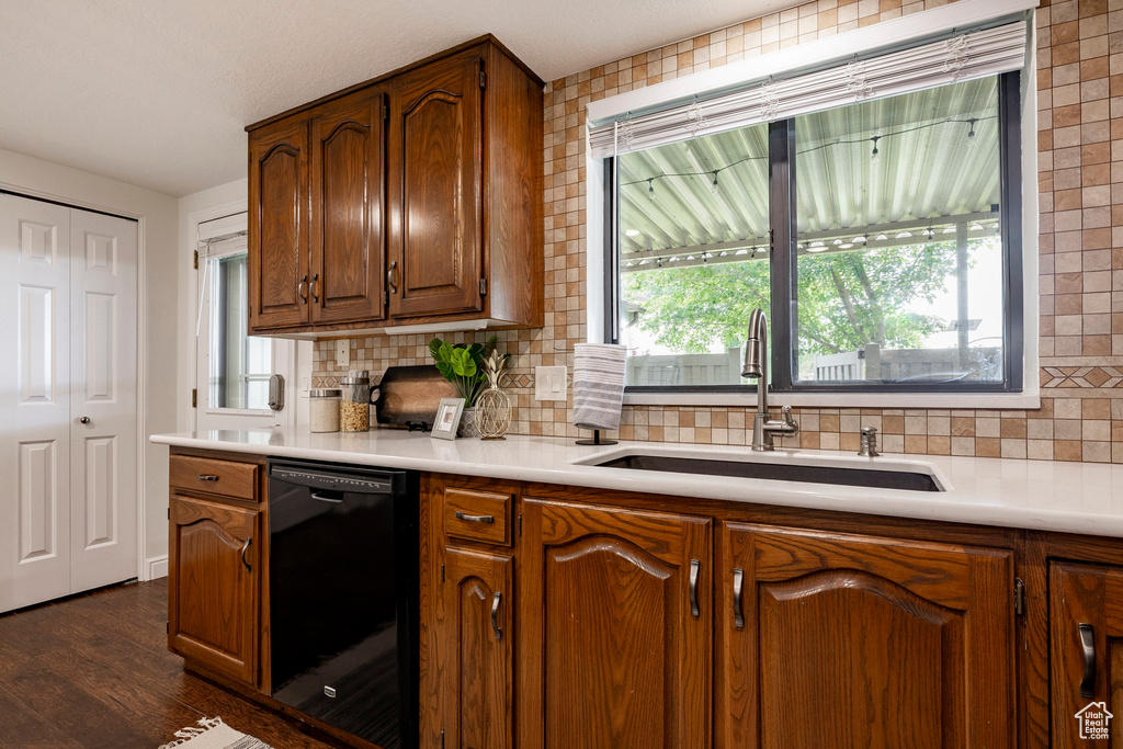 Kitchen featuring black dishwasher, decorative backsplash, and light countertops