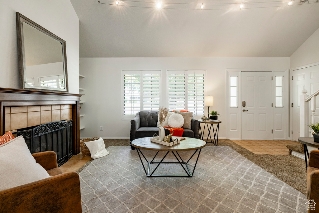 Tiled living room featuring lofted ceiling and a tiled fireplace