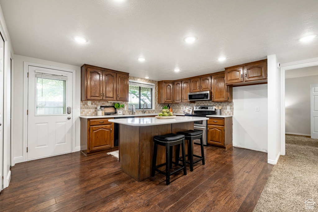 Kitchen with stainless steel microwave, light countertops, dark wood finished floors, tasteful backsplash, and recessed lighting