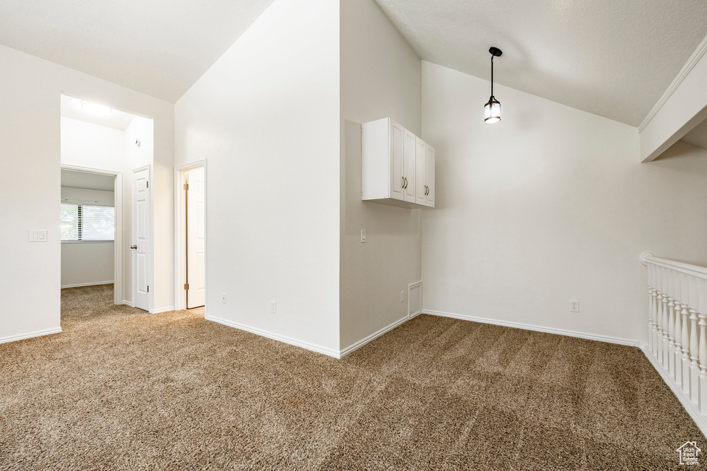 Empty room featuring light carpet and high vaulted ceiling