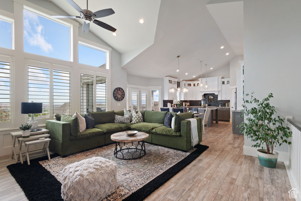 Living room with ceiling fan, high vaulted ceiling, recessed lighting, and light wood-type flooring