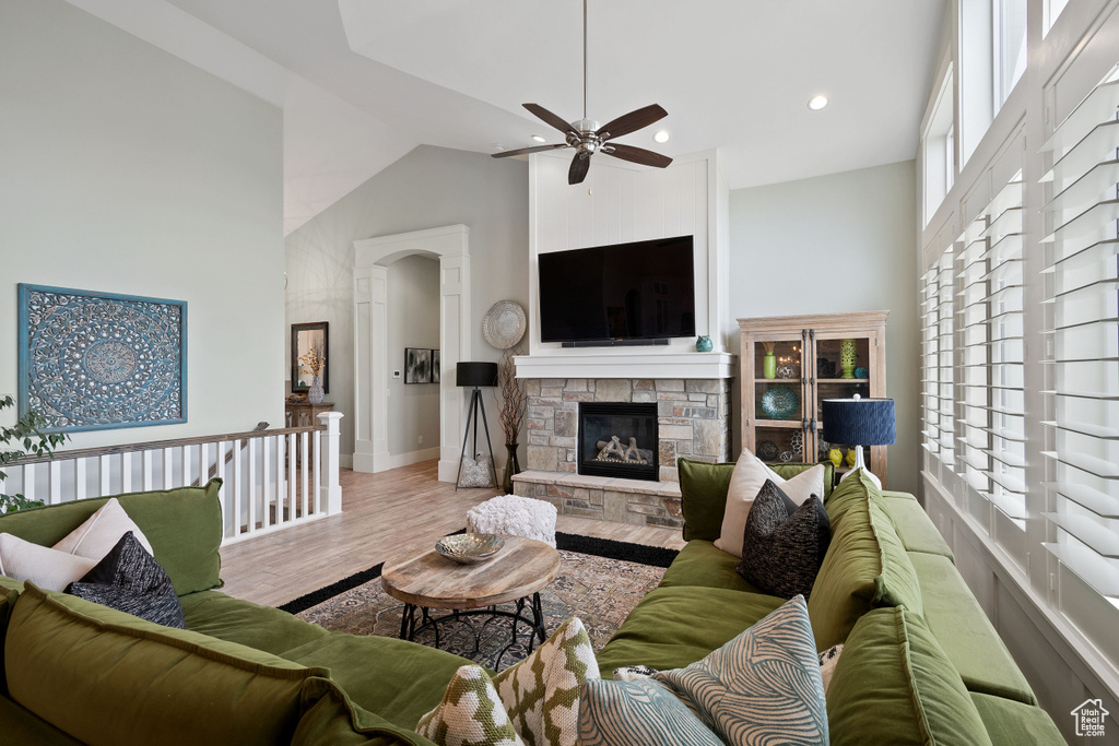 Living room with high vaulted ceiling, ceiling fan, wood finished floors, plenty of natural light, and a fireplace