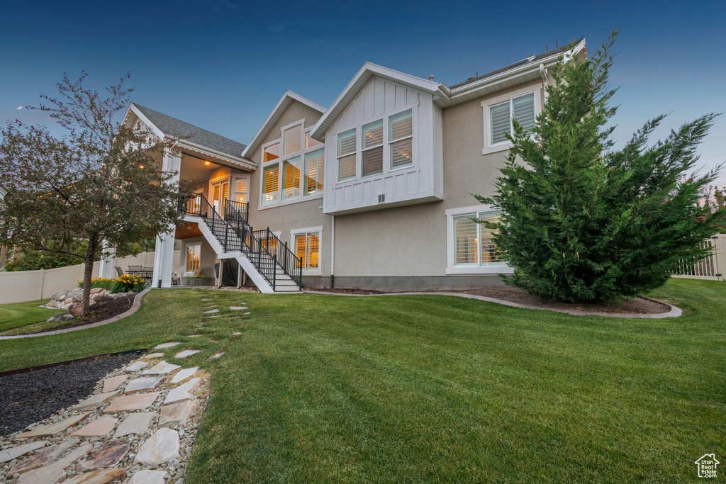 Back of property featuring stairway, stucco siding, board and batten siding, and a sunroom