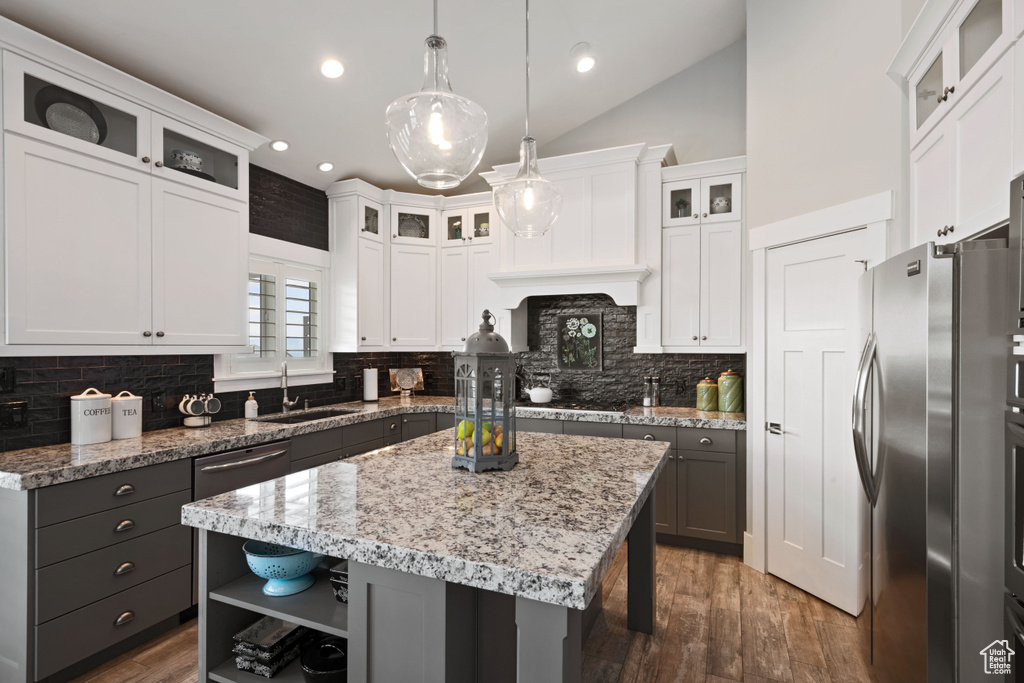Kitchen featuring stainless steel appliances, a center island, wood finished floors, white cabinetry, and open shelves