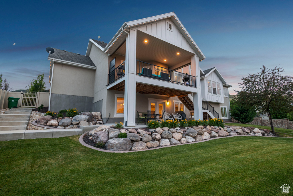 Back of house with stairs, a patio area, a balcony, board and batten siding, and a gate