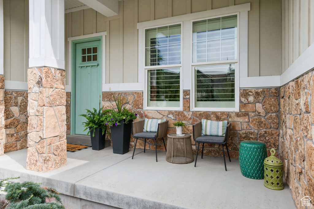Property entrance with stone siding, board and batten siding, and a patio area