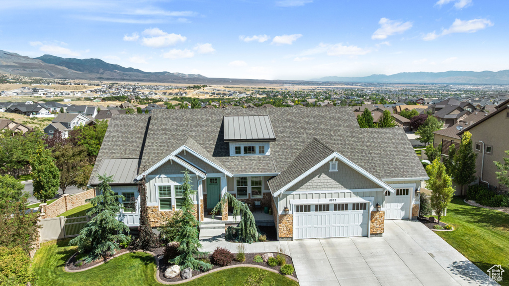 View of front facade featuring stone siding, a garage, a mountain view, concrete driveway, and a shingled roof