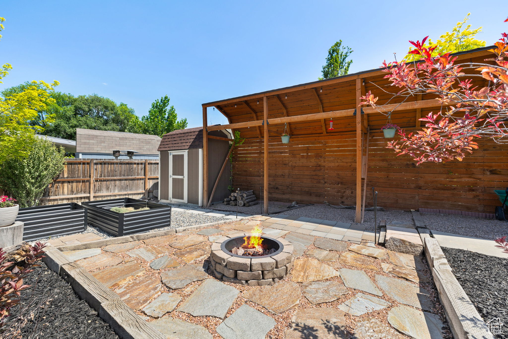 View of patio featuring a fire pit and a storage shed