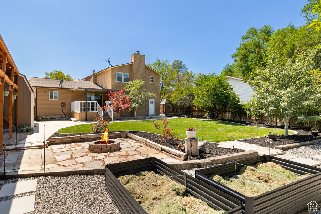 Fenced backyard with a fire pit, a vegetable garden, and a patio