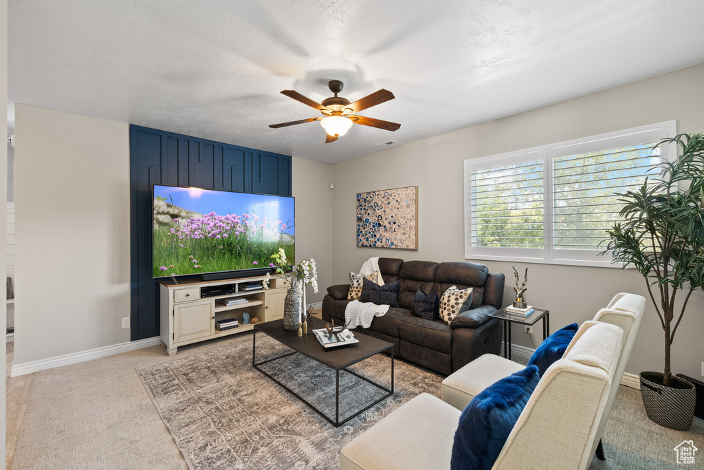 Living area featuring light carpet and ceiling fan