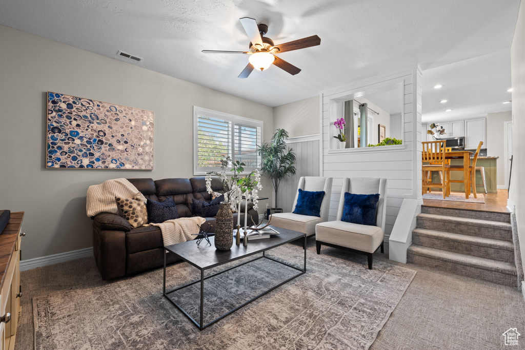 Carpeted living area featuring ceiling fan and recessed lighting