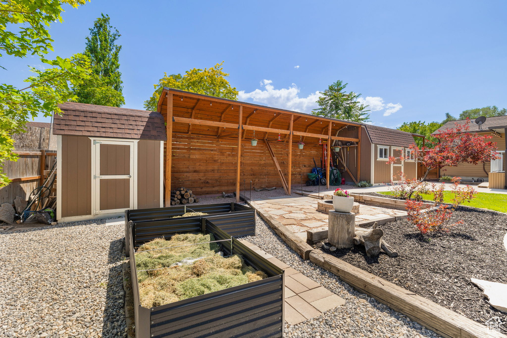 Back of house with a shed, a garden, and a patio area