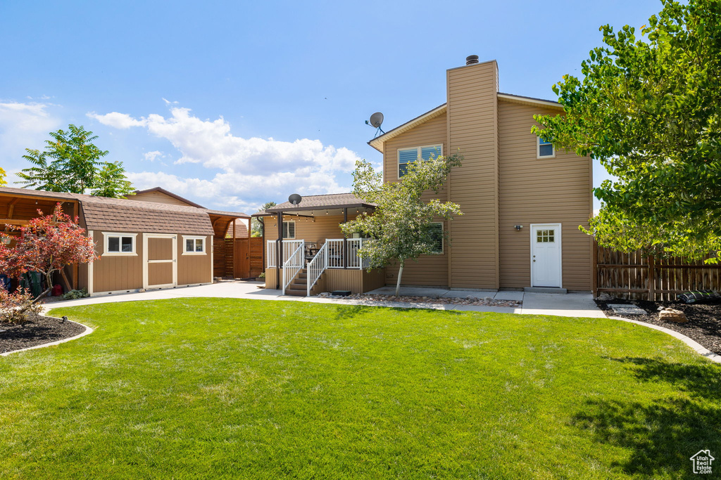 Rear view of property featuring a storage shed, a chimney, and a patio