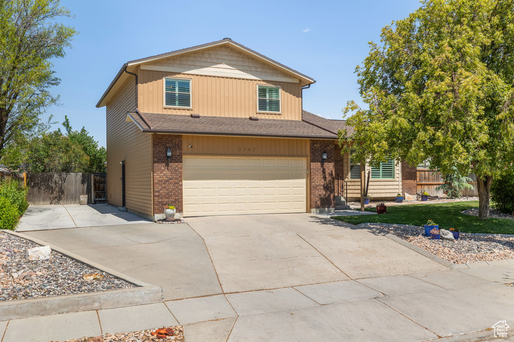 View of front of home with concrete driveway, an attached garage, brick siding, and roof with shingles
