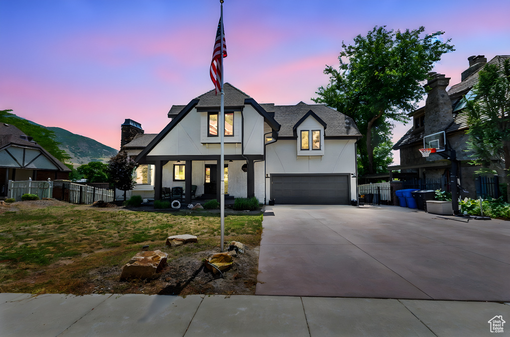 View of front of property with driveway, an attached garage, stucco siding, a porch, and roof with shingles