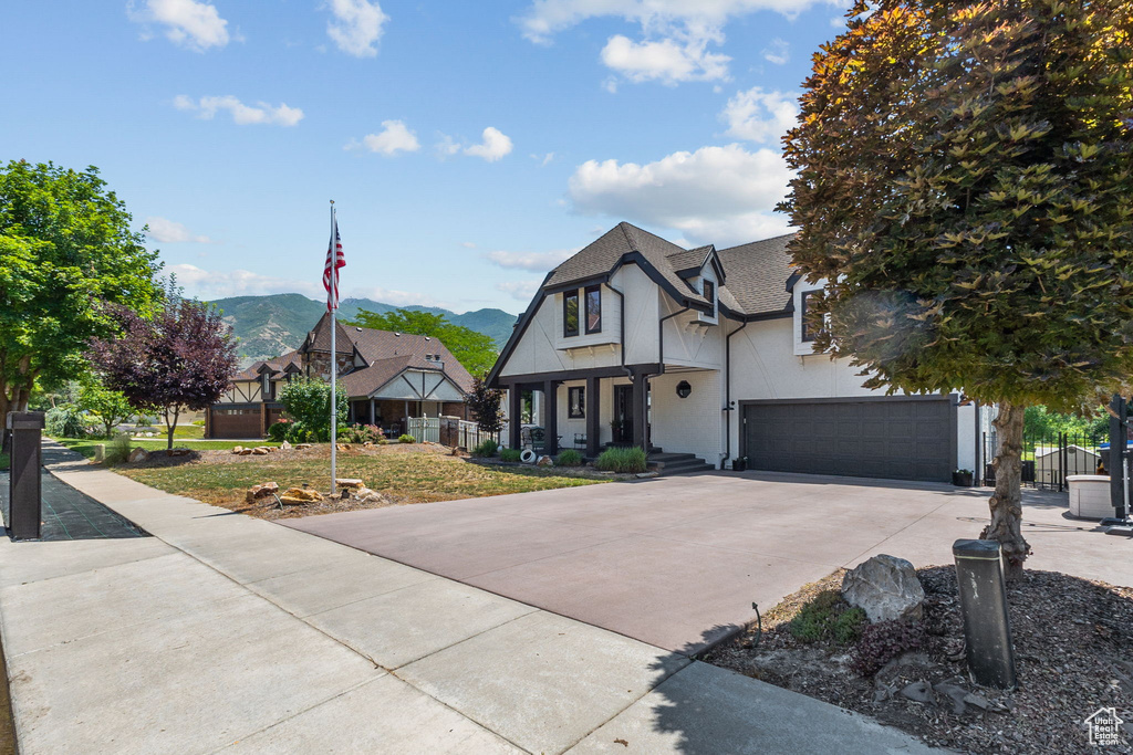 Tudor home with concrete driveway, a shingled roof, a mountain view, and an attached garage