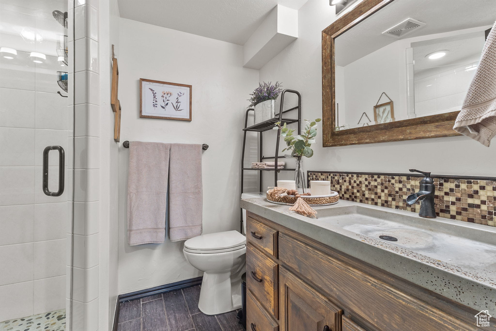 Full bath with a stall shower, vanity, decorative backsplash, and wood finished floors