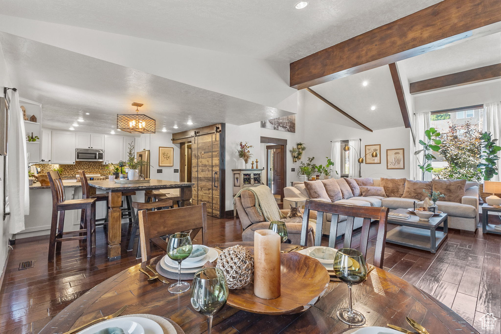 Dining area featuring a barn door, recessed lighting, and dark wood-type flooring
