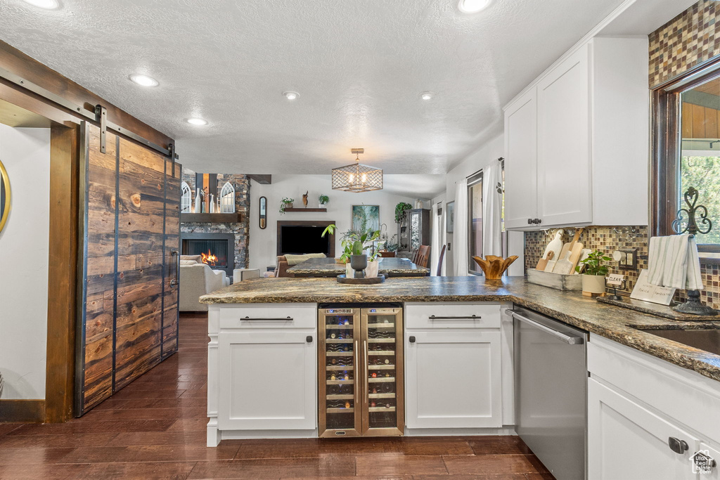 Kitchen with wine cooler, dishwasher, a peninsula, open floor plan, and white cabinets