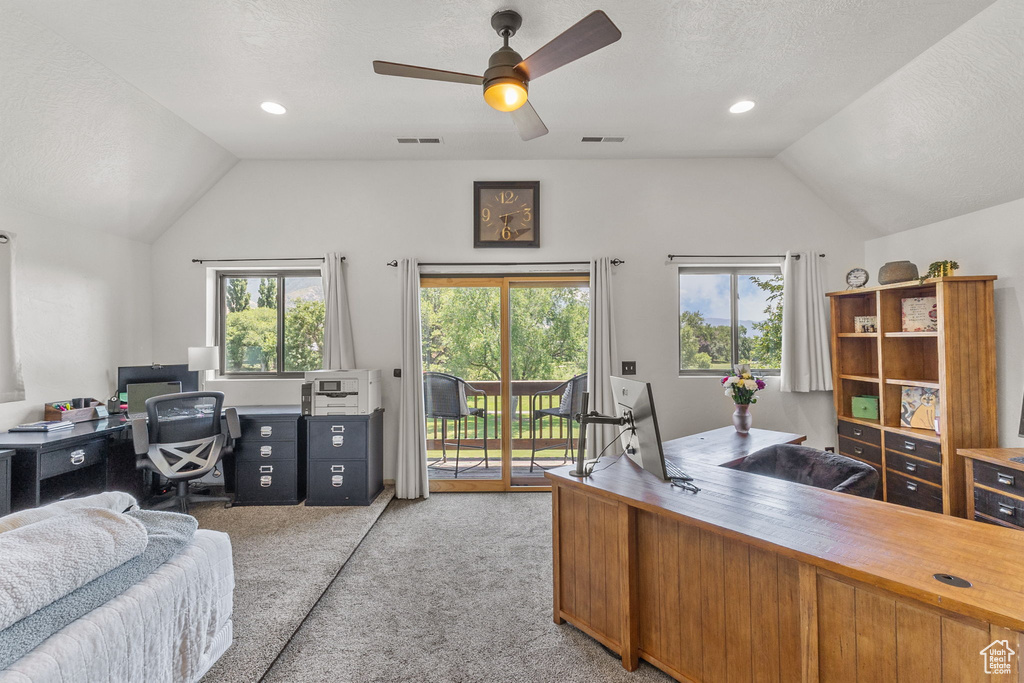 Home office with vaulted ceiling, light carpet, ceiling fan, and a textured ceiling