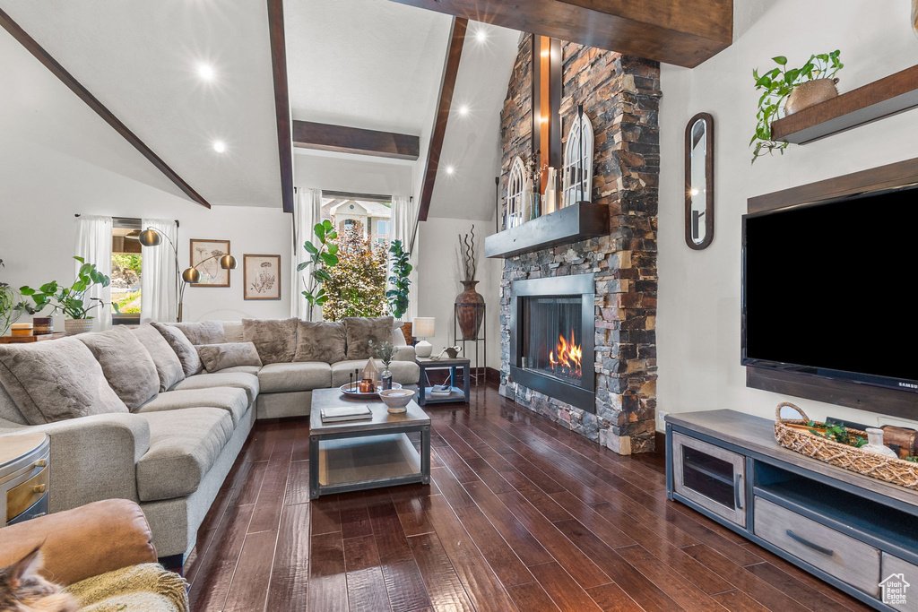 Living room featuring beamed ceiling, a stone fireplace, wood finished floors, high vaulted ceiling, and recessed lighting
